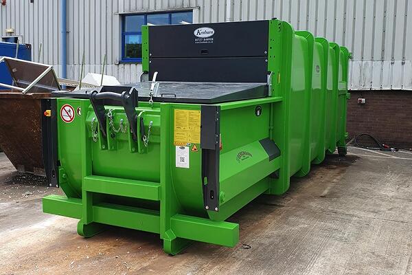 Waste compactor next to pile of rubbish 